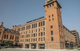 Historic brewery building in Wrocław, Poland showcasing classic red brick architecture under clear blue sky.